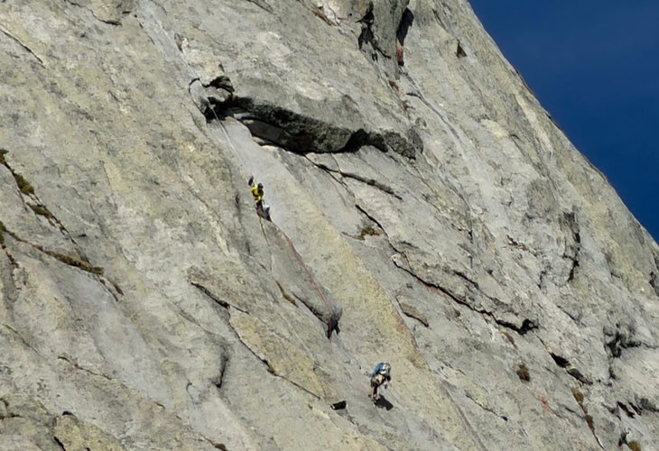 Rescuers on the wall helping climbers lower off the route. A blank rock face.