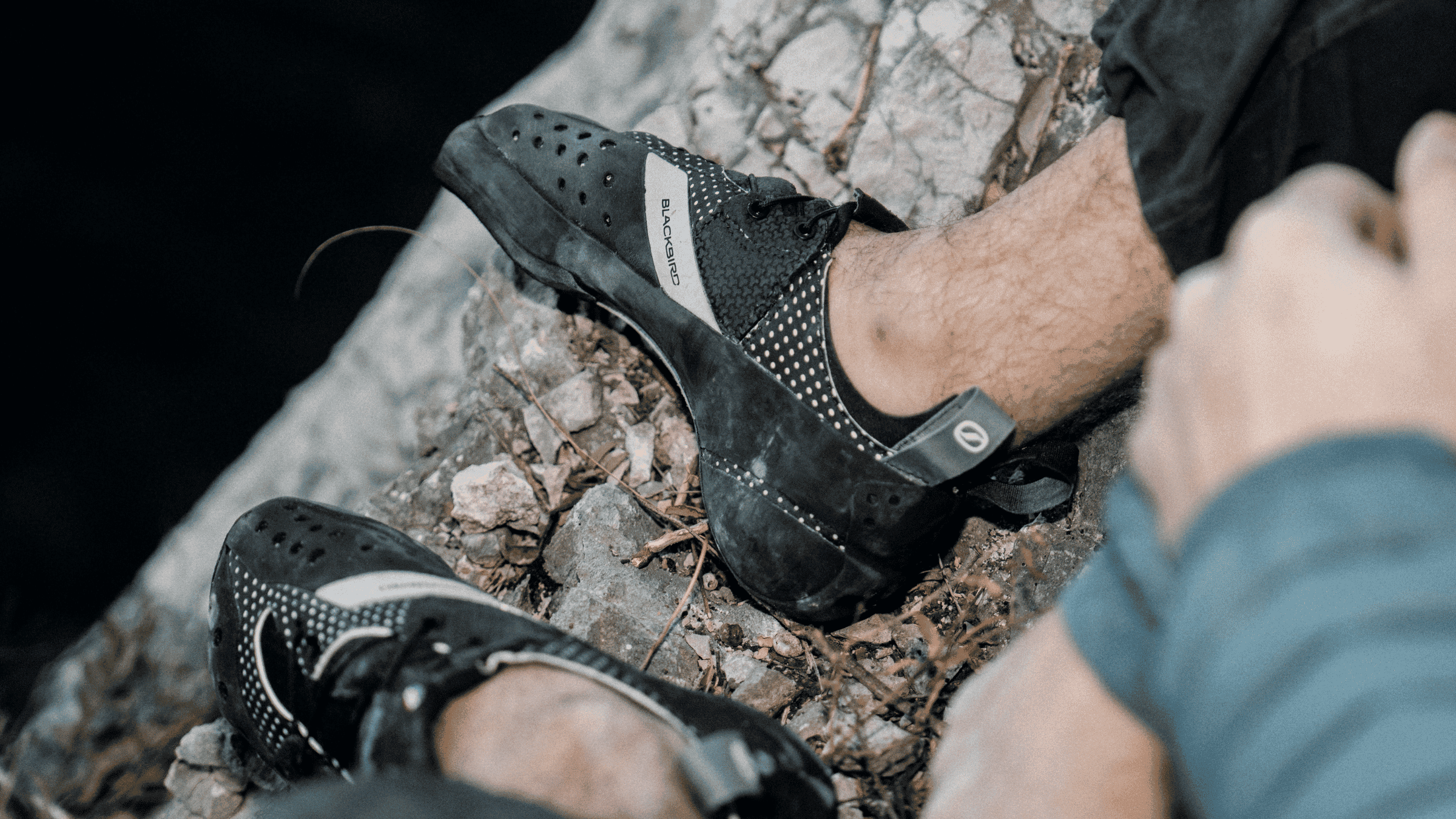 Scarpa Blackbird worn on a rocky ledge outdoors.