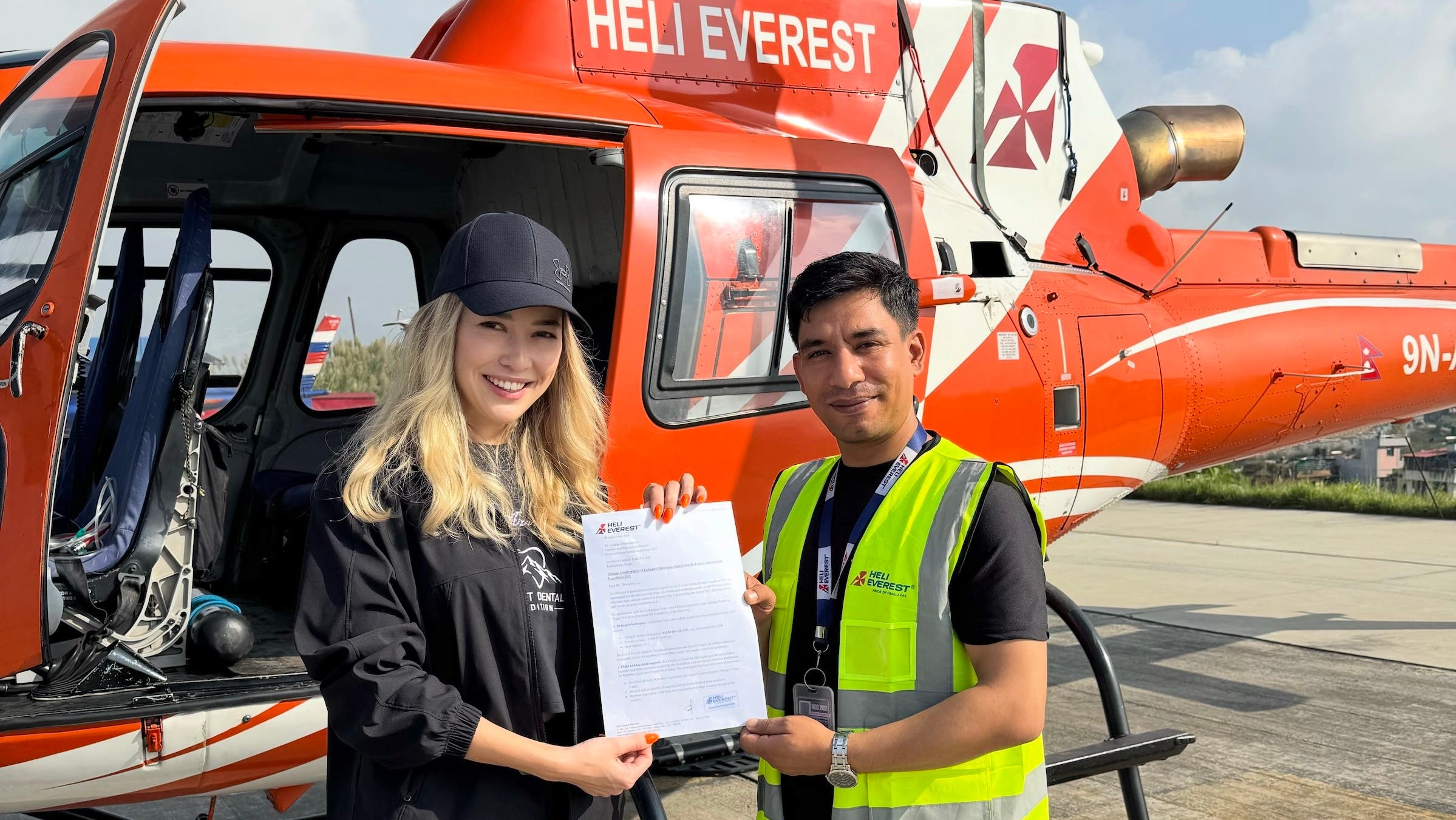 everest dental clinic: a dentist and a pilot pose in front of a helicopter