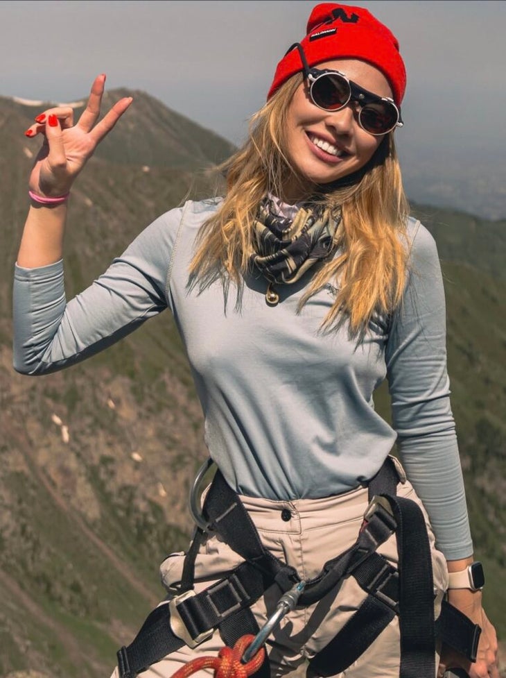 a woman flashes a peace sign in the mountains