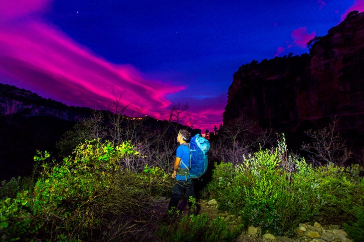 A climber with a backpack and a colorful sunset