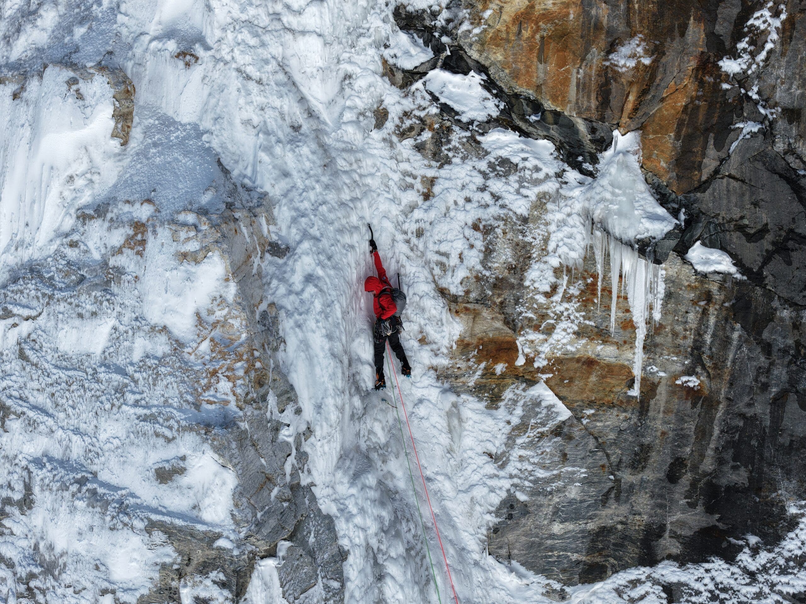man in red climbs ice on new route in nepal