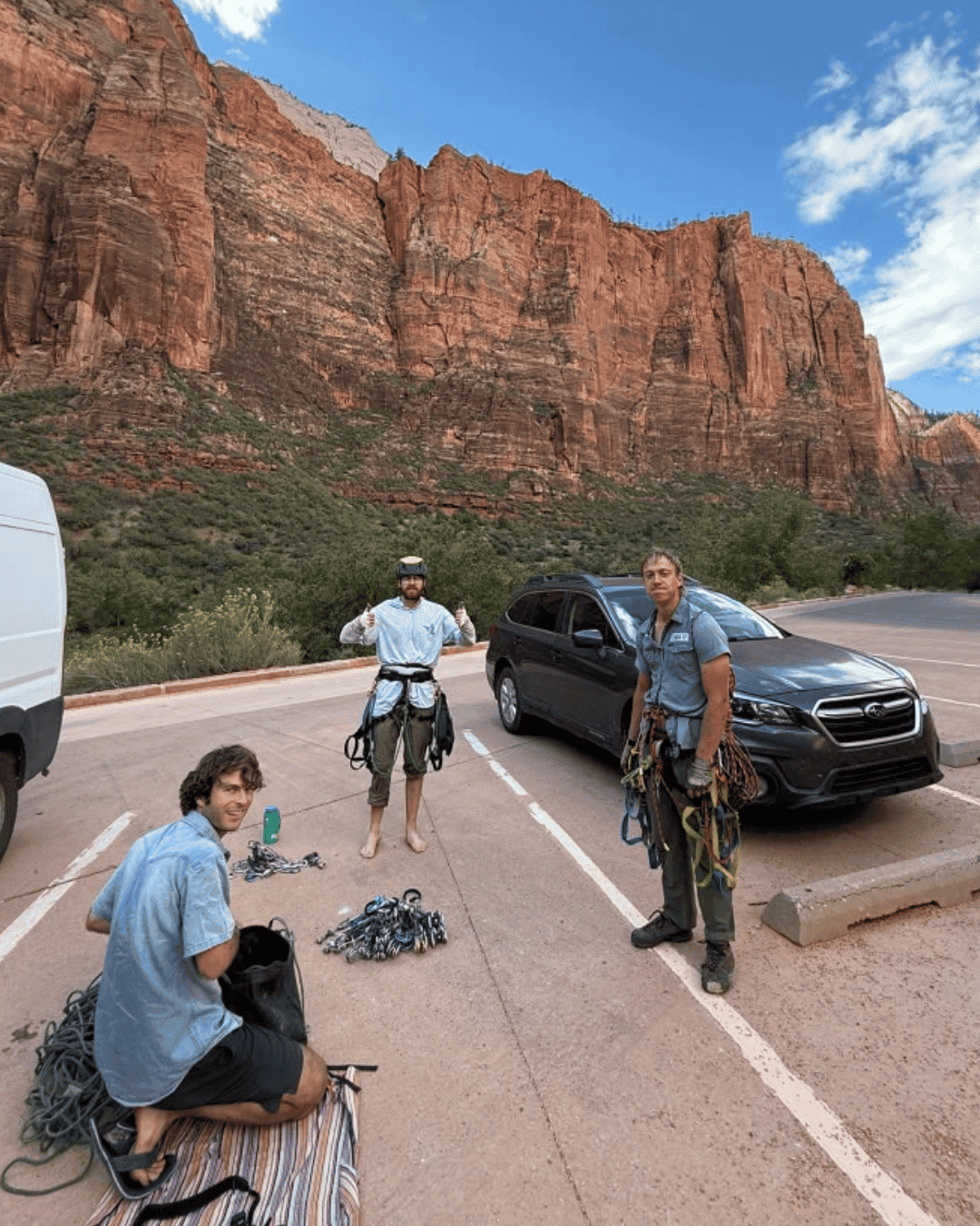 three climbers in a parking lot in zion