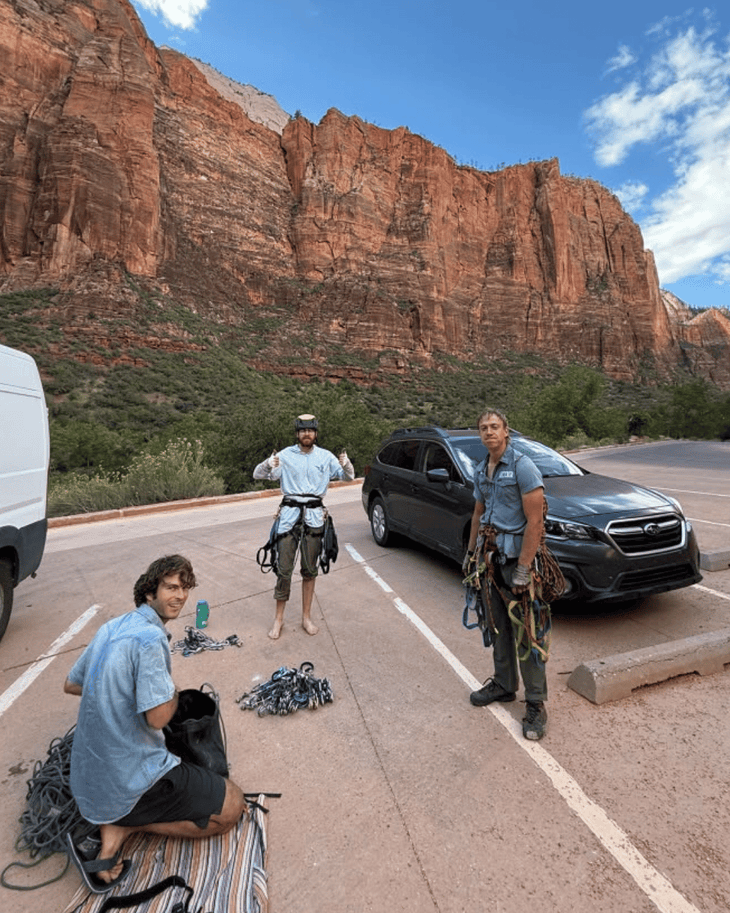 three climbers in a parking lot in zion
